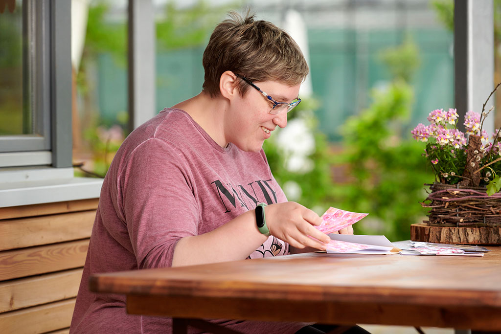 eine Frau sitzt am Tisch und arbeitet an einer Grußkarte