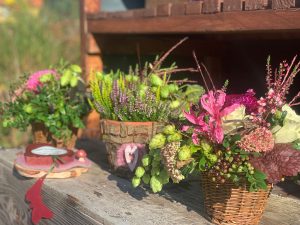 Holztisch mit verschiedenen Herbstgestecken aus der Floristik