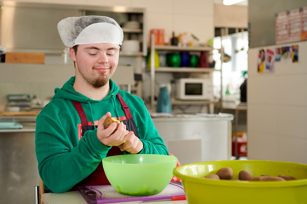 ein junger Mann schält Kartoffeln